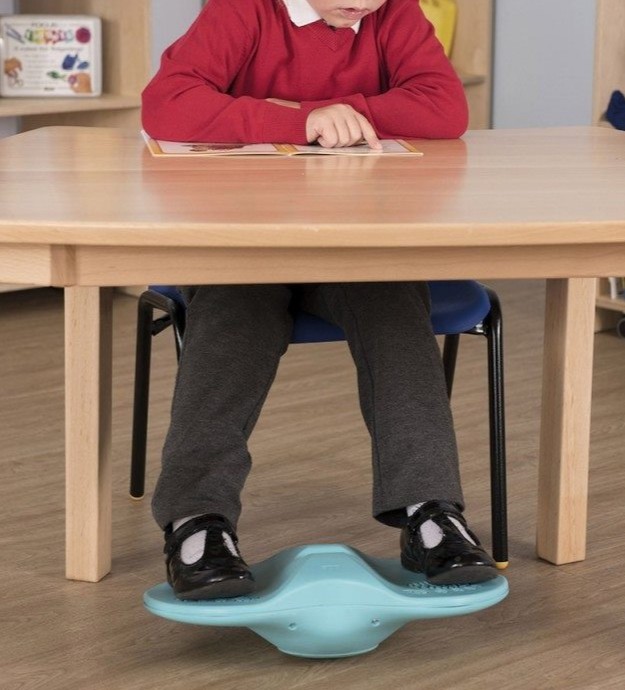 Enfant utilisant le Fidgety feet sous ses pieds pendant qu'il travaille à son bureau